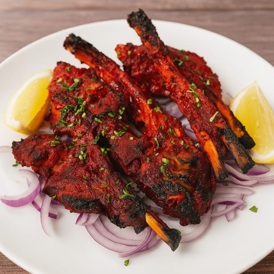 HotBits Indian Cuisine's grilled lamb chops, garnished with lemon wedges and red onion slices.